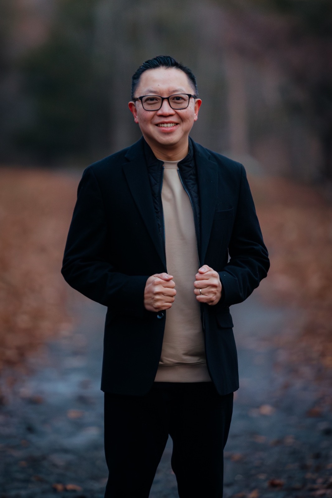 Dux Raymond Sy smiling outdoors in a dark jacket